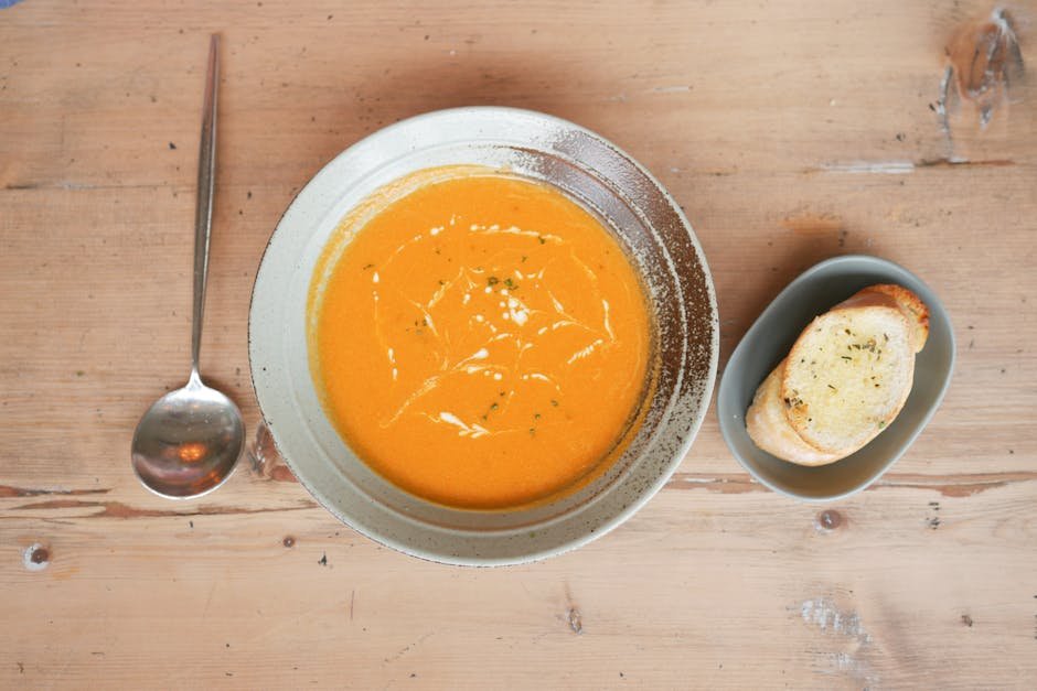 Delicious pumpkin soup served with garlic bread on a rustic wooden table, perfect for a cozy meal.