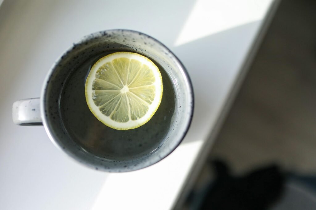 Close-up of a mug with a slice of lemon floating in water, bathed in natural light.