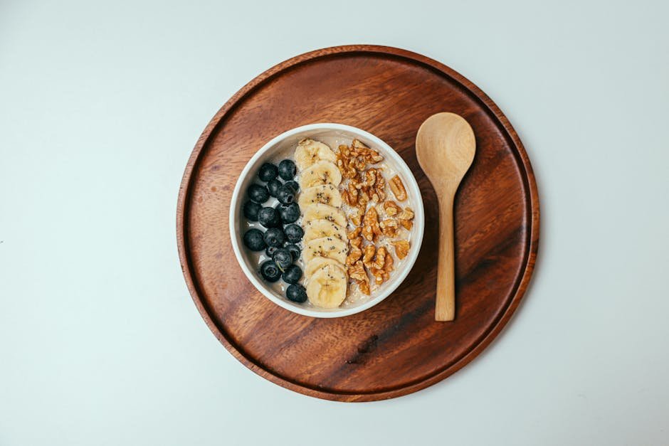Delicious oatmeal bowl with blueberries, banana, and walnuts on a wooden tray.